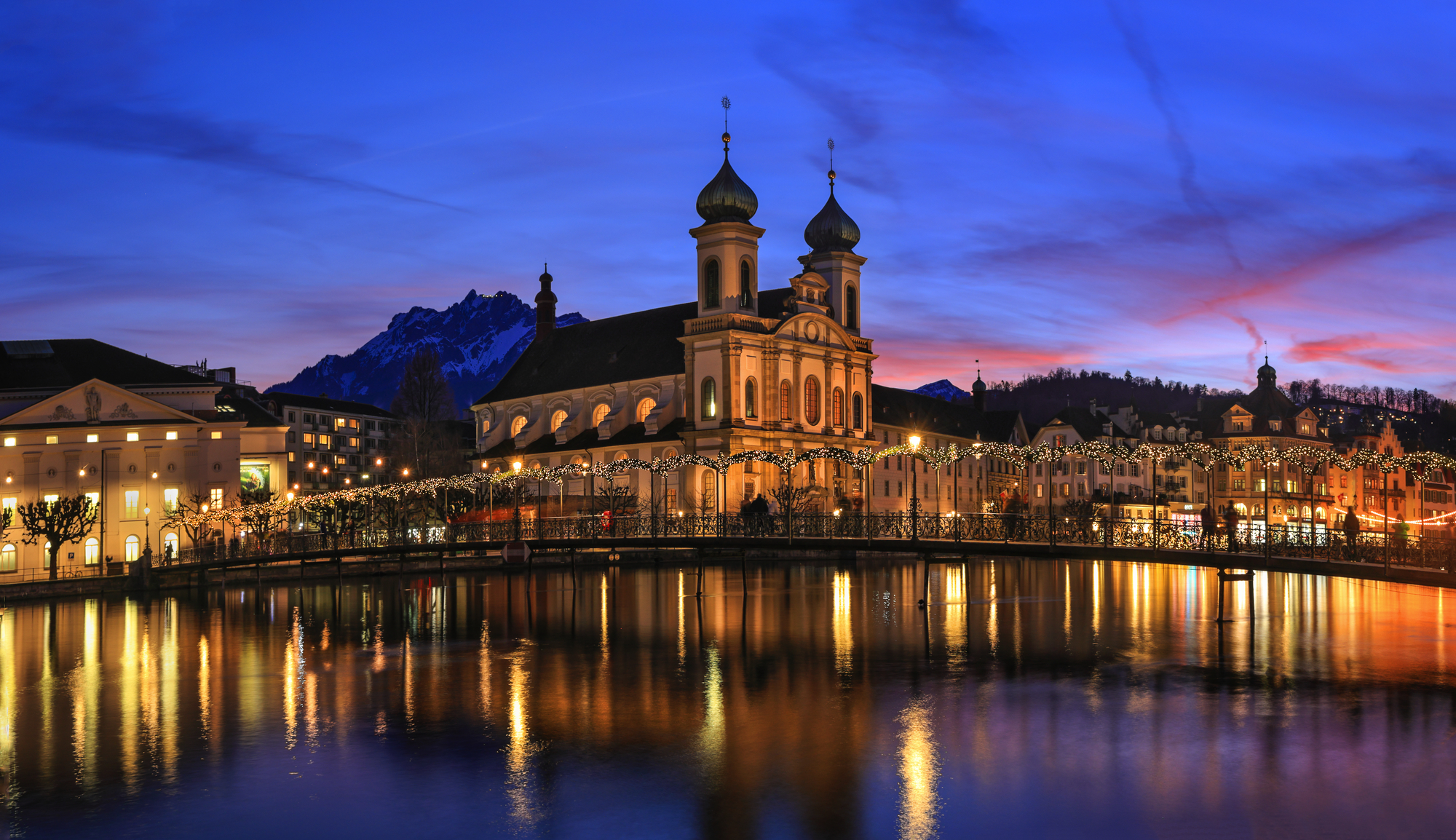 Splendid sunset over the  Jesuit church with Pilatus mountain at background in the evening and Rathaussteg in Christmas illumination, Lucerne, Switzerland